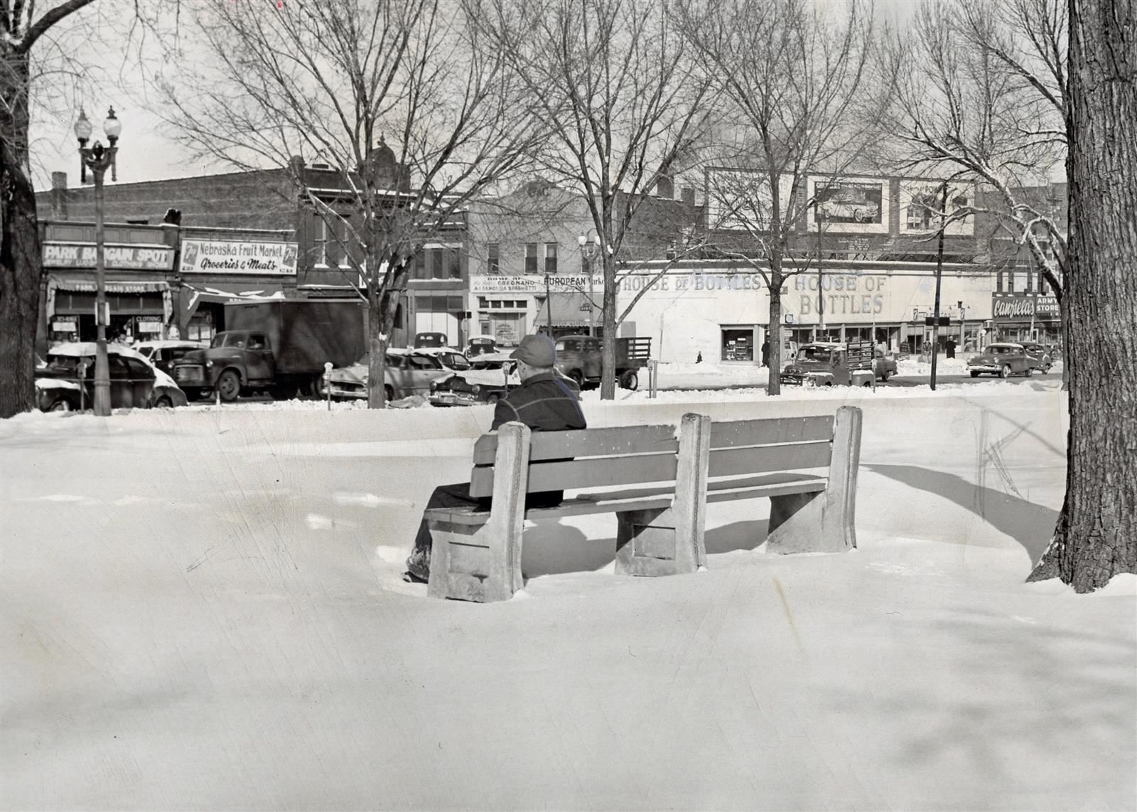 A person sits on a bench in Jefferson Park on a snowy day